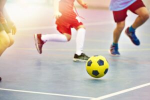 Three children play soccer outside.