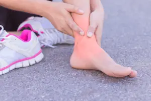a woman massaging her ankle to relieve her peroneal tendonitis pain