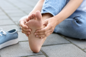 Person holding forefoot in pain, illustrating Hallux Limitus.